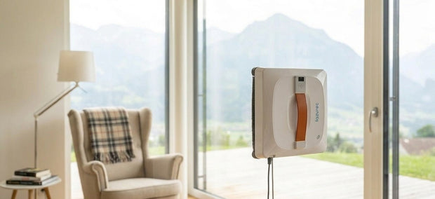 Lazurec A9 Pro Fensterputzroboter an einer Glasfront mit Strom- und Sicherungskabel, helle Leseecke mit Bergblick