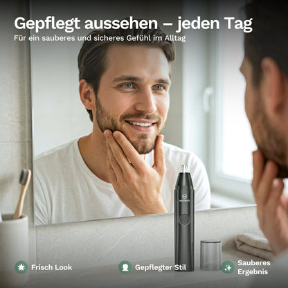 Mann betrachtet sich im Spiegel und überprüft seinen gepflegten Bart, neben ihm ein elektrischer Trimmer für die tägliche Pflege.